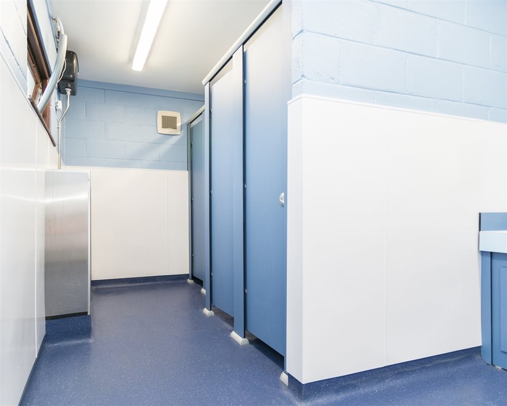Quadro Toilet Cubicle in 'Air Force Blue' with stainless steel urinal trough opposite