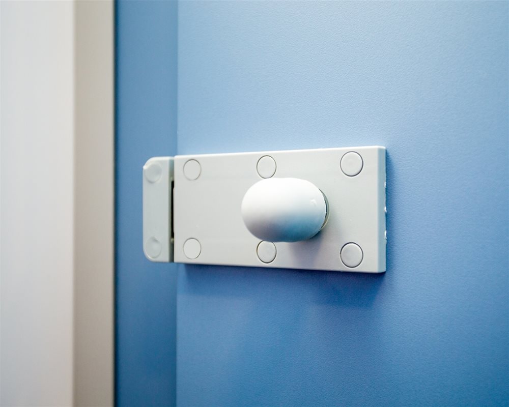 Silver plastic lock body on 'Air Force Blue' toilet cubicle door.