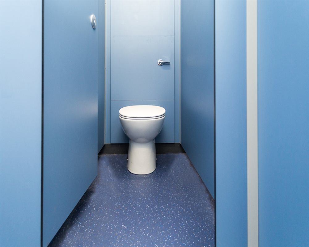 Quadro Toilet Cubicle in 'Air Force Blue' with door open showing white back to wall toilet pan and lever flush on 'pale blue' duct panels.