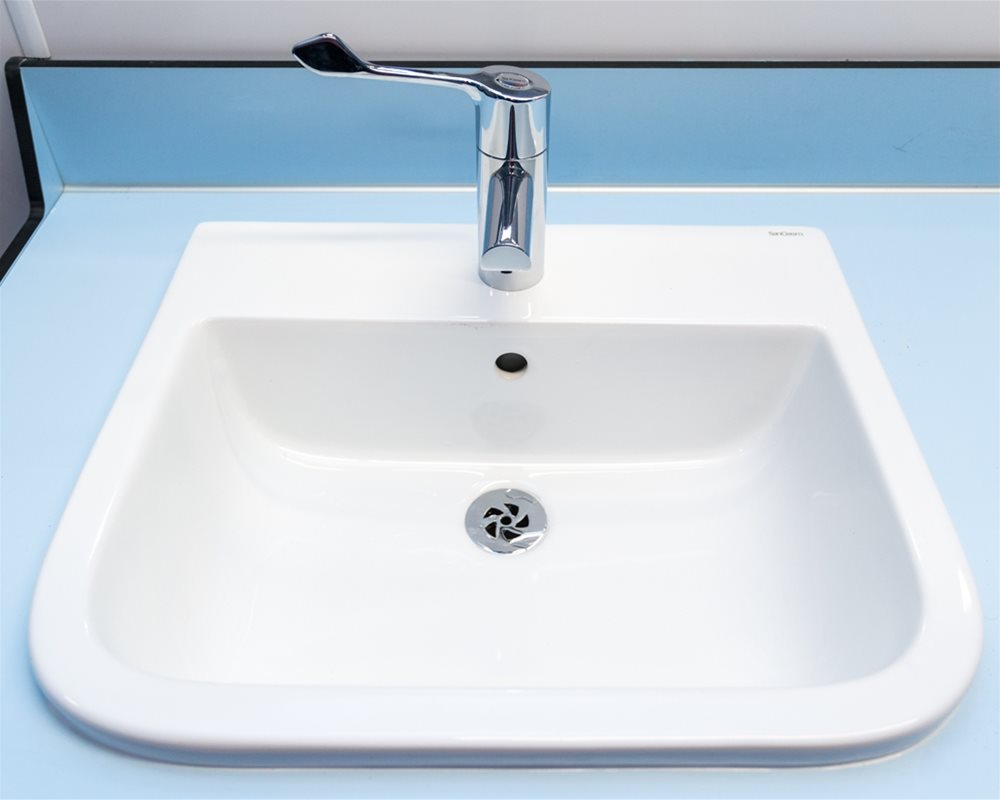 White ceramic countertop washbasin with long lever tap.