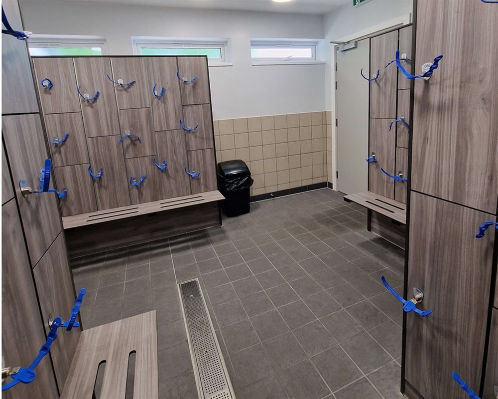 Swimming pool changing room with 'Grey Oak' lockers and integrated benching with wristband keys.