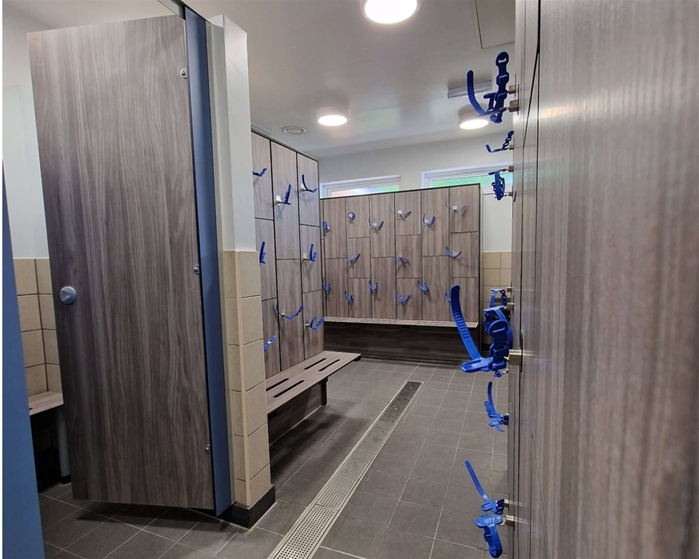 Swimming pool changing room with 'Baseline' changing cubicles in 'Grey Oak' and lockers with wristband keys and integrated benching.