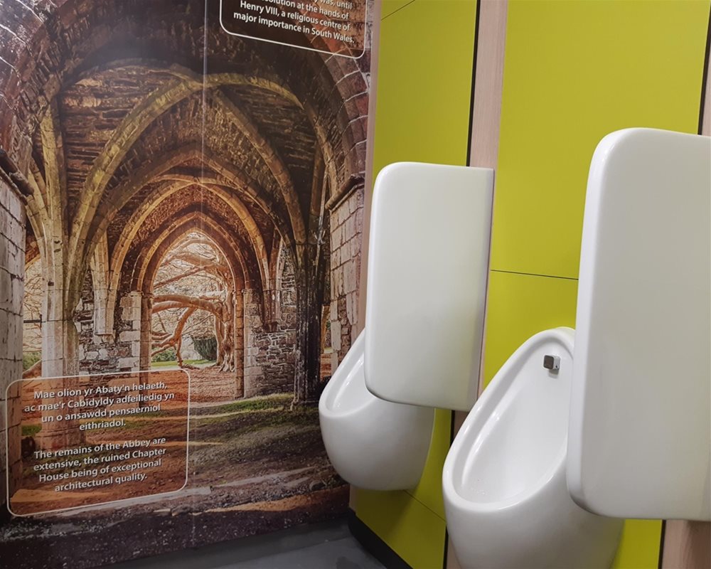 Ceramic white wall hung urinals and ceramic white urinal separators on 'Lime Green' panels and 'Bleached Oak' flashgaps.