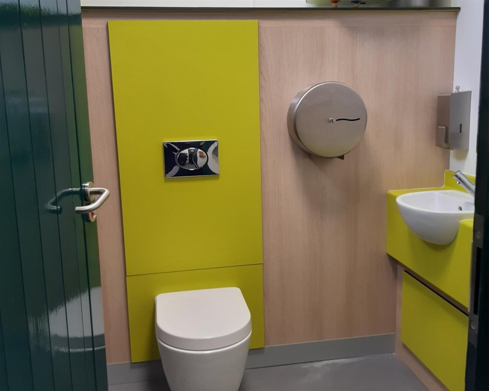 Wall hung WC half height duct set in 'Lime Green' and 'Bleached Oak' in superloo format with semi-recessed vanity unit.