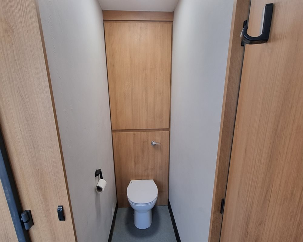 Toilet Cubicle with dark grey fittings with Fast Track Quick Delivery IPS Duct Panels in Oak with back to wall WC and lever flush