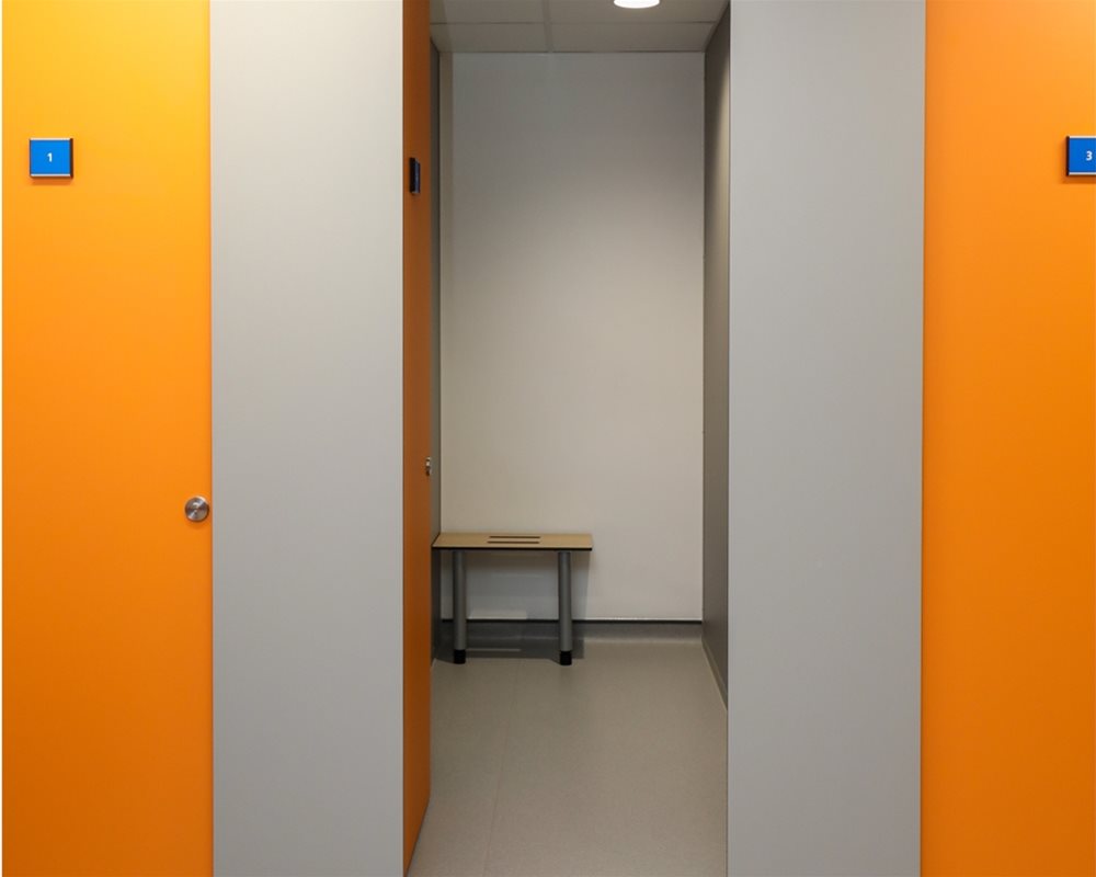 HiZone full height toilet cubicle with 'Orange' and 'Light Grey' pilasters offering total privacy as a changing cubicle with benching inside.