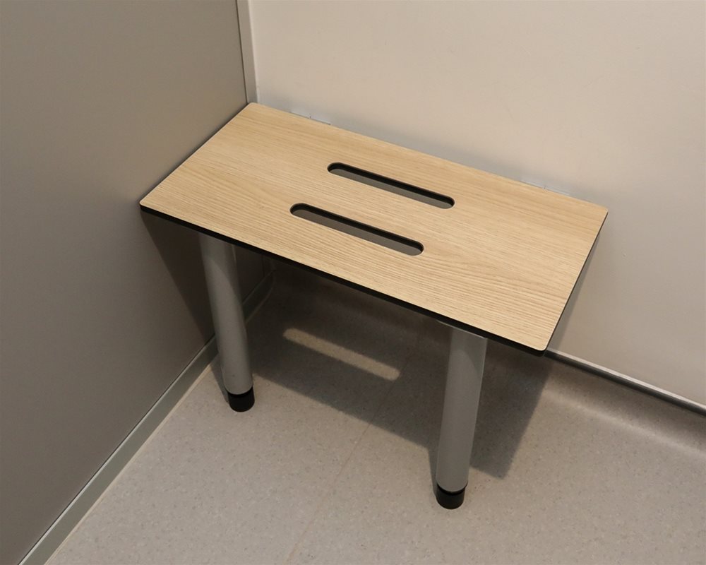 Cantilever Bench in SGL material in Oak colour with tubular legs for extra support inside full height toilet cubicle.