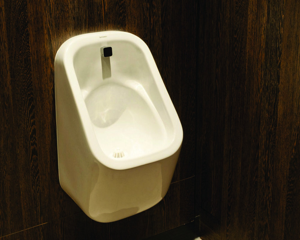 Ready plumbed wall hung White Marden Urinal with concealed cistern and trap behind duct shown in 'American Walnut'