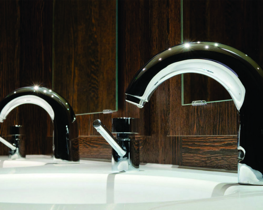 Solid Surface Counter top vanity with chrome sensor mixer tap and soap dispenser, mirrors panel mounted to 'American Walnut Ducts'