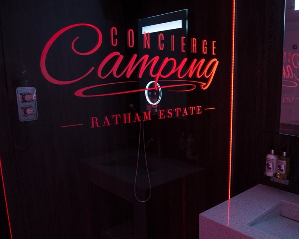 Concierge Camping branded shower screen lit up in the dark
