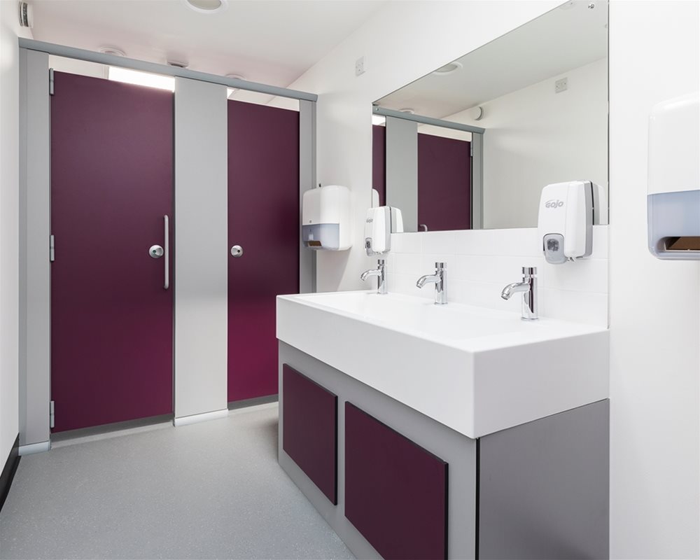 Quadro toilet cubicles in 'Mulberry' purple and 'Elysian' white Solid Surface Washtroughs for Norwich High School