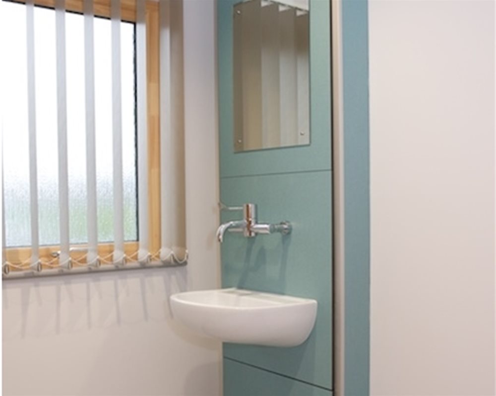 Traditional boxed out healthcare unit in 'Bay Leaf' green with SanCeram basin and tap